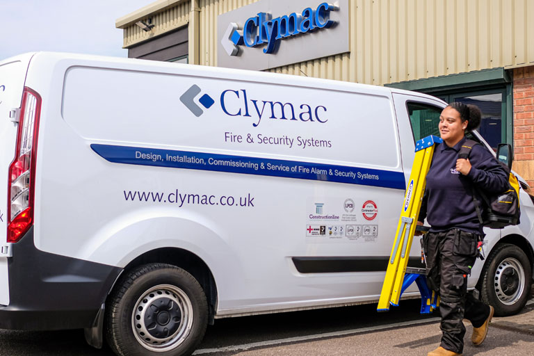 Woman employee with step ladder next to Clymac company vehicle